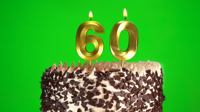 Lighting number 60 golden birthday candle on festive cake. Green screen, chromakey. Birthday cake on 60th anniversary