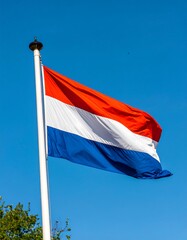 Dutch flag waving against a clear blue sky