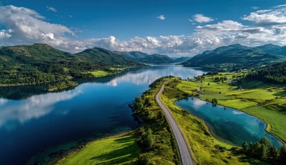 Aerial Panorama - Winding Road Dividing Azure Lake and Lush Green Mountains Under Bright Sky.