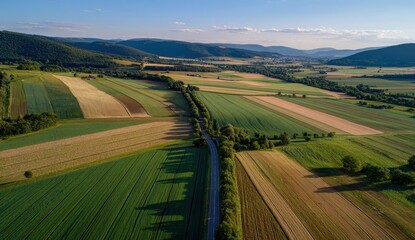 Golden Hour Aerial - Patchwork Fields, Rural Road, and Rolling Hills in Serene Countryside Landscape.