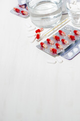 thermometer and a glass of water, medicines in tablets and capsules, vertical