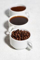 Three types of coffee - beans, ground and espresso on a white background, vertical