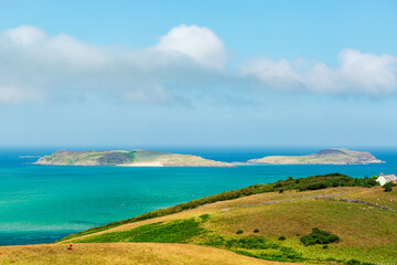 Obraz premium Hidden Scotland. NC500 route. Scenic coastal landscape with islands, green hills, and turquoise sea under clear sky