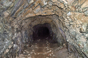 Podziemny tunel sztolniowy używany do wydobycia uranu, z surowymi, skalistymi ścianami i rozrzuconym gruzem. © Pol Badger