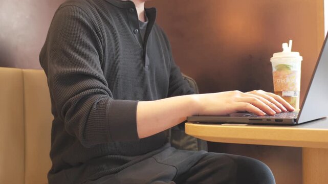A middle-aged man residing in Shenzhen, Guangdong Province, China, is working diligently on his laptop while sitting on a wooden chair in a Chinese restaurant.