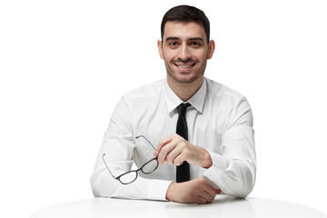 Cheerful young manager sitting at a desk holding black glasses and listening with interest and content