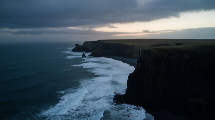 Dramatic cliffs meet the turbulent sea under a moody sky. Coastal landscape showcases rugged beauty and powerful waves crashing against the shore. An exploration of nature's raw force.