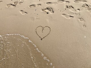 Herz und  Spuren im Sand am Strand im Urlaub am Meer