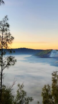 Eruption of the Bromo volcano during sunrise in the Bromo-Tengger-Semeru National Park, East Java, Indonesia. The Tengger volcanic caldera is in cloud and fog. Dawn. 4К