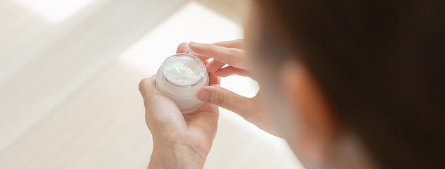 Close-up woman using skin care serum cream in daily routine.