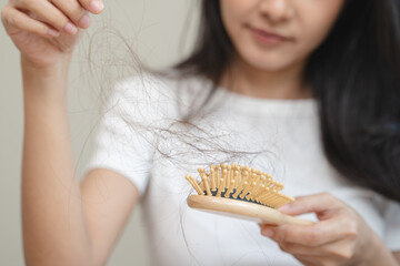 Close-up young woman brushing her hair and have many hair loss on the comb