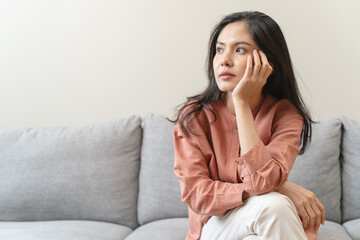 Stressed female feeling depressed and lonely on the sofa in the house.