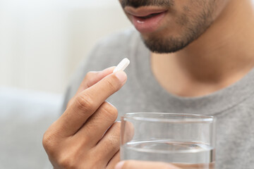 Young man taking painkiller and drink water to healing from cold flu.