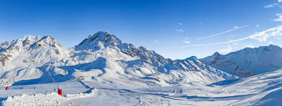 panorama on ski resort  in tarentaise valley, savoie with snowy mountain range and ski slope under blue sky
