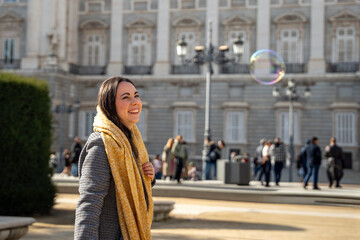 Fototapeta premium Smiling woman enjoying a sunny day filled with bubbles in a lively city square