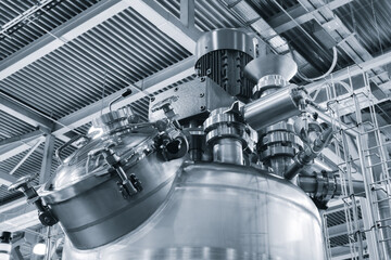 Large industrial machine in pharmaceutical factory with many stainless steel pipes, taps and other...