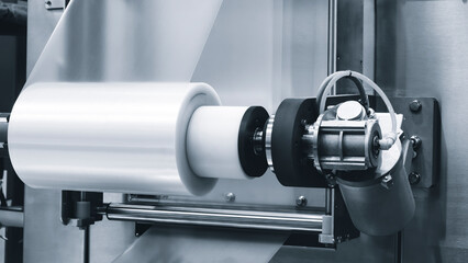 Automatic polyethylene plastic bag production machine with lighting effect. Close-up of the roller of the plastic bag production machine in the light blue scene. product packaging concept