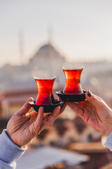 A woman's and a man's hands holding glasses of Turkish tea