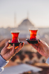 A woman's and a man's hands holding glasses of Turkish tea