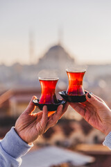 A woman's and a man's hands holding glasses of Turkish tea