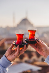 A woman's and a man's hands holding glasses of Turkish tea