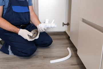 Plumber working on installing sink drain pipe