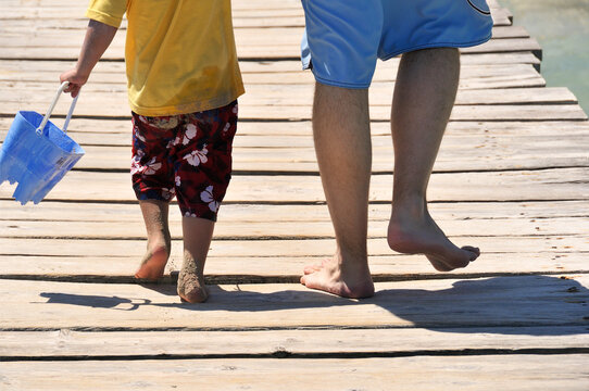Playa de Muro, Muro beach, Alcudia, Mallorca, Majorka, Balearic Islans, Spain, Europe - young father and little boy walking hand in hand on wooden pier