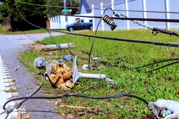 Power pole is down on grass with tangled wires scattered near road following hurricane storm in peaceful neighborhood. © ungvar