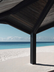 A beach pavilion with a dark roof against a white sand beach