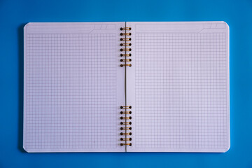 Top view of Notebook on blue background, space for text. Blank inside of a white spiral notebook...