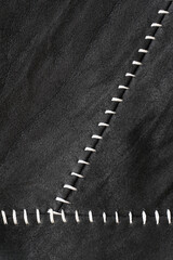 Crumpled black suede textured vertical background with white contrast stitching