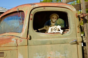 skeleton driver in an old rusty truck