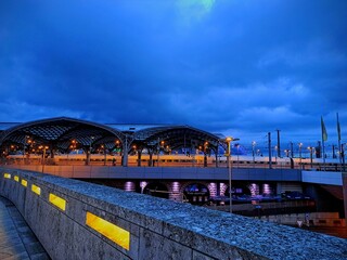Cologne train station at night, December 19, 2025. City evening landscape. Night blue sky. Europe, Germany, Cologne city. bridge at night