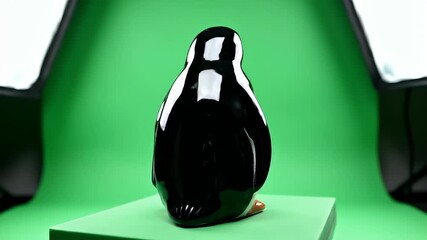Cute Penguin Figurine Display on Green Background.