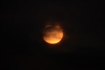 Partial solar eclipse effect with glowing sun and atmospheric clouds at dusk or dawn