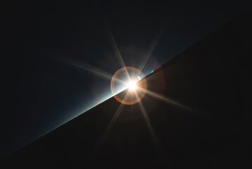 Radiant sunburst lens flare with circular halo peeking over a sharp abstract dark edge