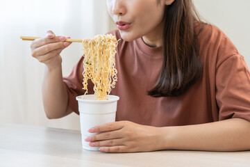 Happy temptation, attractive asian young student woman, cute girl using chopsticks eating instant ramen, noodles soup from a cup, cooking meal fast food lifestyle of traditional japanese person.