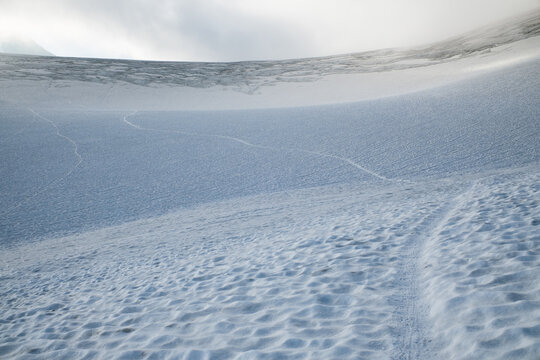 Minimal alpine glacier slope with snow texture and trail