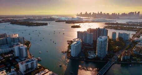 Approaching the tranquil waterscape with multiple boats on. Aerial perspective on Brickell Key in Miami, USA at golden hour.