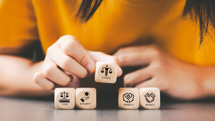 Code of conduct in business concept. Wooden blocks with code of conduct icons; code, integrity, honesty, respect, and ethics, the foundation of a strong corporate code of conduct. Corporate ethics. 