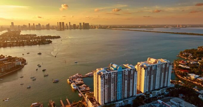 Waterscape of Biscayne Bay in the golden light of sunset. High-rise skyline of Miami at backdrop. Aerial view.