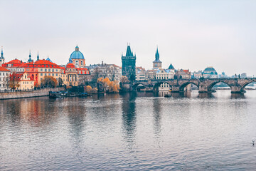 Charles Bridge over Vltava River in Prague, Czech Republic. Serene view of medieval stone arch bridge connecting Old Town with Lesser Town, historic architecture and Vltava river under overcast sky