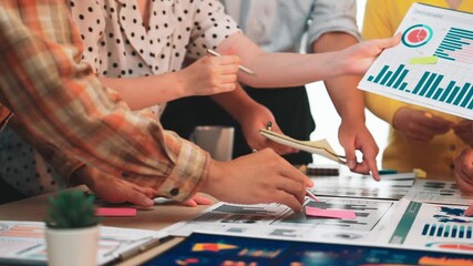 A diverse business team engages in an analytical discussion over financial reports and colorful charts in a bright office environment, showcasing teamwork and collaboration. SACTR - Powered by Adobe