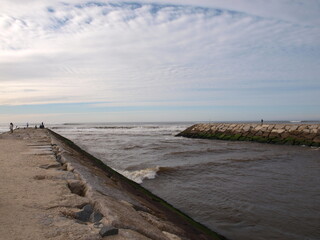 Obraz premium Stone Jetty Extending into the Sea Under Cloudy Sky at Veira de Leiria, Portugal