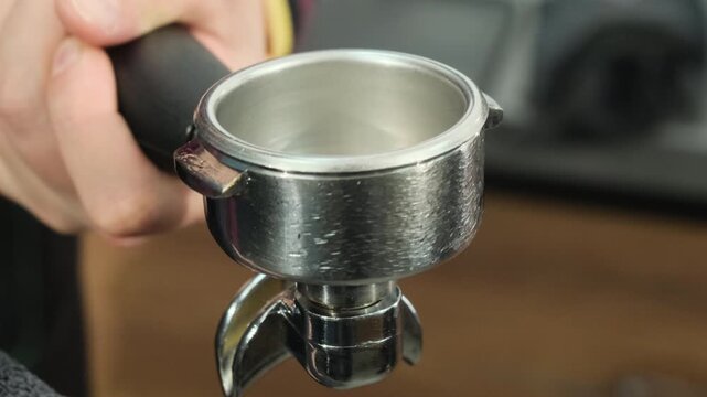 Bartender wipes metal holder of coffee machine dry with towel. Cleaning kitchen equipment after use to maintain hygiene standards slow motion