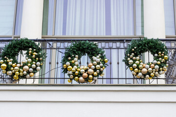 Three Christmas wreaths on the balcony of an office building.
