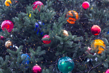 A Christmas tree with colorful balls and garland. Part of the frame.