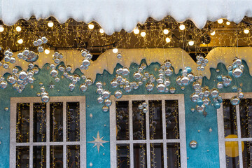 Christmas decoration: A decorative house with windows, twinkling lights, and silver balls. Part of the frame.