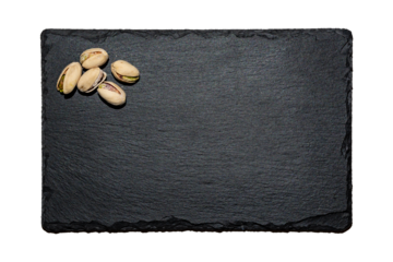 Cinco pistachos tostados salados encima de un plato de pizarra negra, en formato PNG