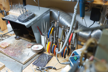 Various professional jewelry pliers and hand tools organized on a workshop workbench.